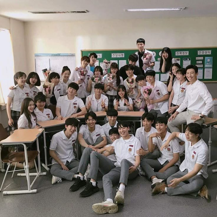 a group of young men and women posing for a photo in front of desks