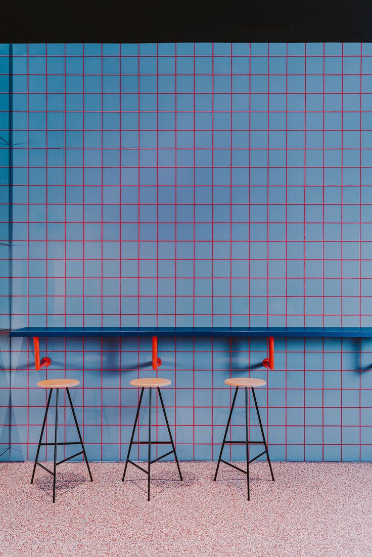 three stools in front of a blue wall