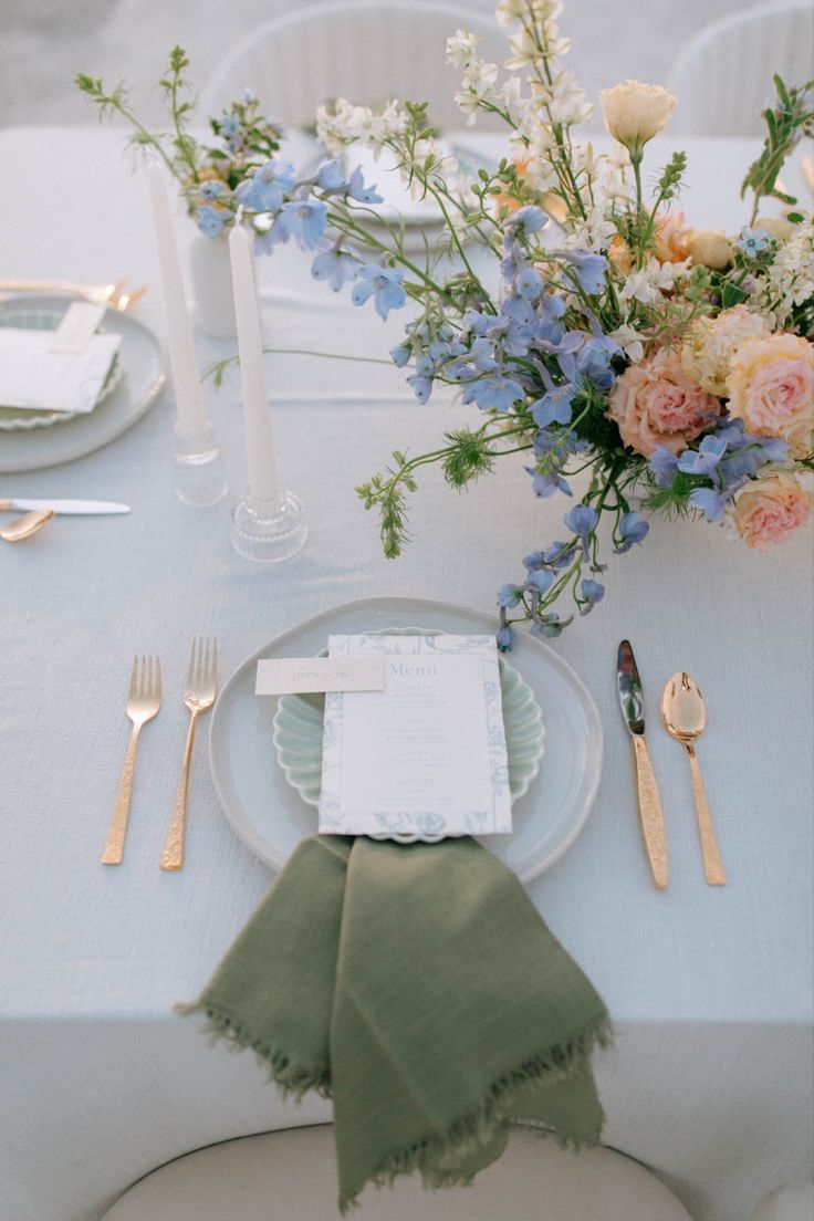 the table is set with flowers, silverware and napkins for dinner guests to enjoy