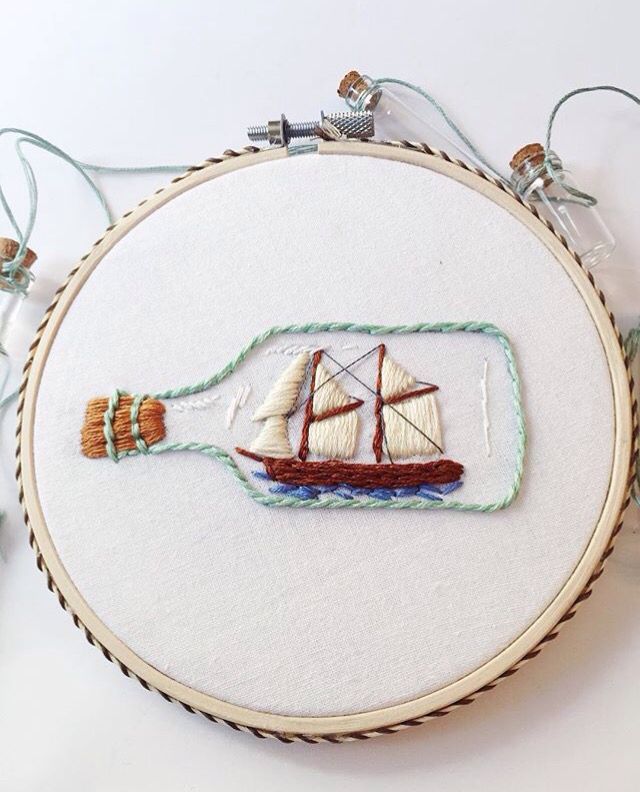 an embroidered sailboat in a bottle on a white background