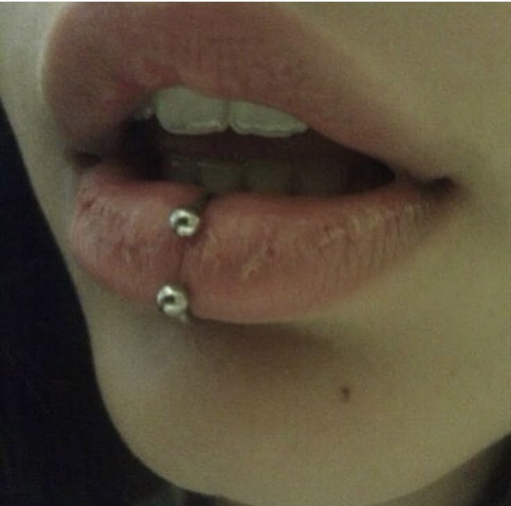 a close up of a person's lips with piercings