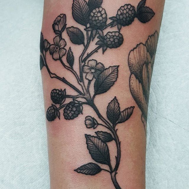 a black and white photo of a flower tattoo on the left leg, with leaves and flowers all over it