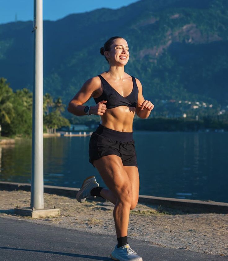 a woman running on the road near water