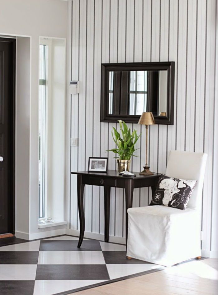 a black and white checkered floor in a living room with a chair, mirror and table