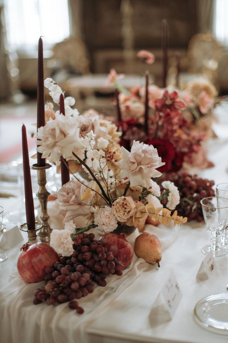 the table is set with flowers, fruit and candles