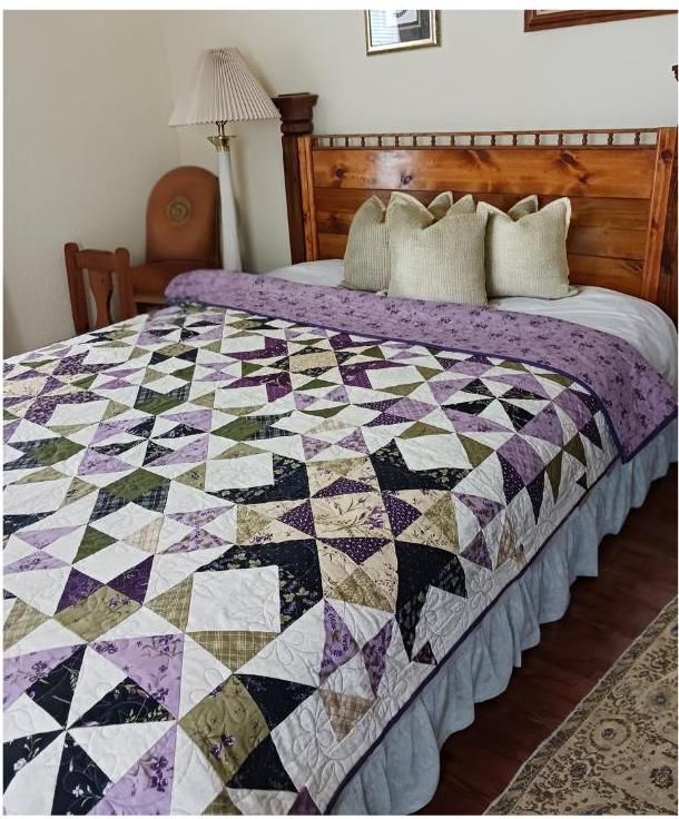 a bed with a purple and white quilt on it