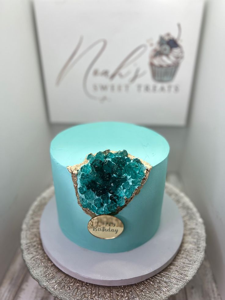 a blue cake sitting on top of a white plate next to a cupcake box