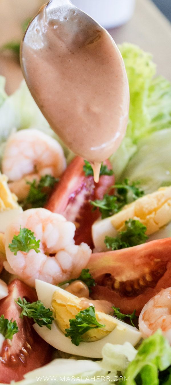 a salad with shrimp, lettuce and tomatoes being drizzled with dressing