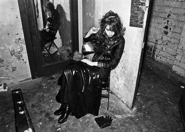 black and white photograph of a woman sitting on a chair in front of a mirror