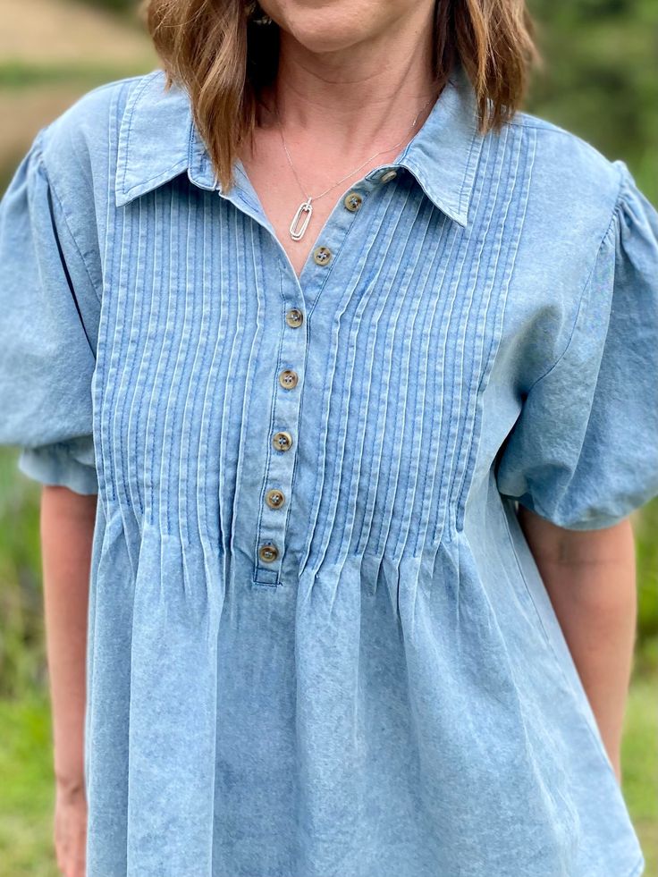 Get ready to rock the denim trend with our Della top! Featuring a button-up collared neck, tucked yoke, and short balloon sleeves with band cuffs, this top is perfect for any occasion. Everyone needs a denim top in their wardrobe, so why not make it this stylish and versatile piece?! True to size. Sizes: Small-Large 100% Cotton Follow tag instructions for washing. Short Balloon Sleeves, Queen Dress, Denim Trends, Dress Gift, Balloon Sleeves, Denim Top, Dress Fashion, Graphic Shirts, Button Up