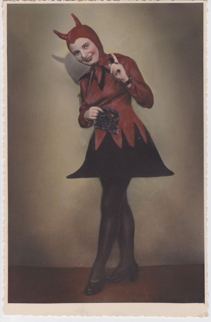 an old photo of a woman dressed in devil makeup and holding a camera with both hands