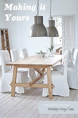 a wooden table with white chairs and two lamps hanging from it's ceiling above