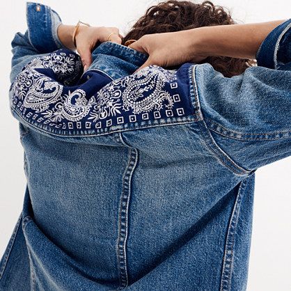 a woman with her back to the camera wearing a jean jacket and bandanna around her neck