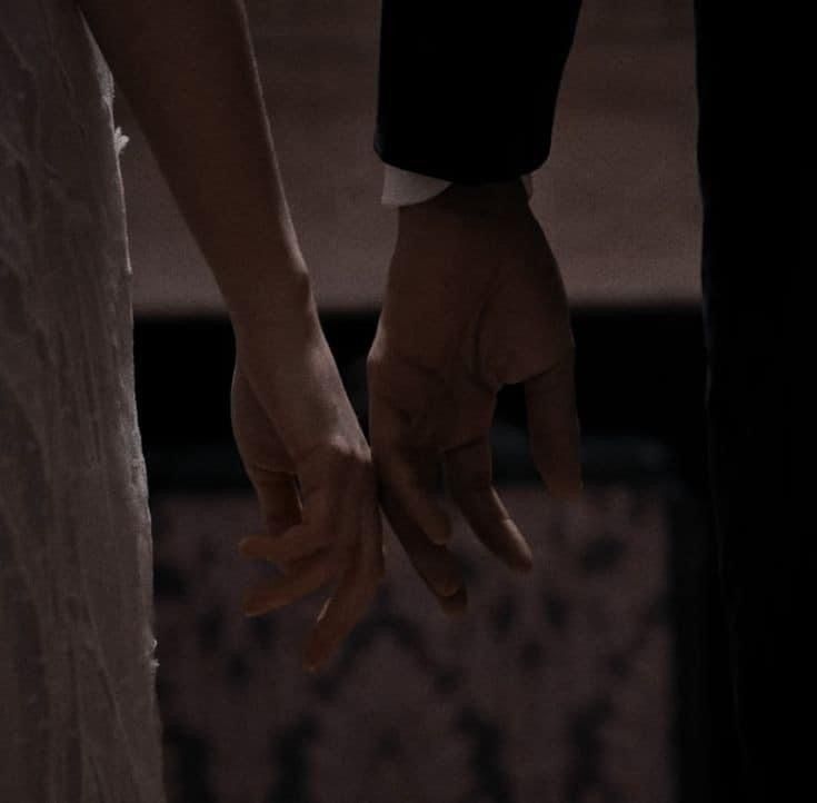 the bride and groom hold hands as they stand close together