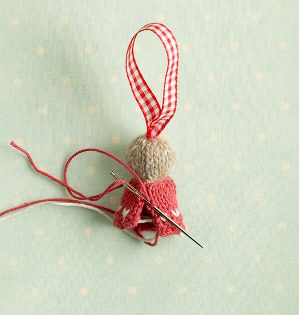 an ornament made out of yarn and knitting needles on a polka dot background