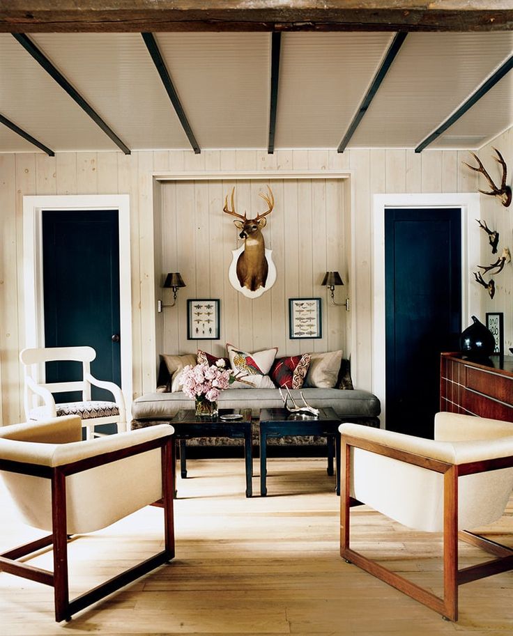 a living room filled with furniture and deer head mounted to the wall above it's fireplace