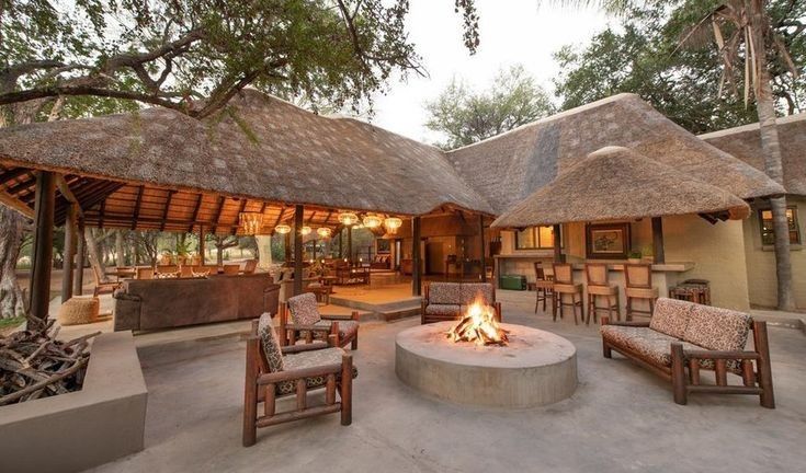 an outdoor living area with chairs, tables and fire pit in the middle of it