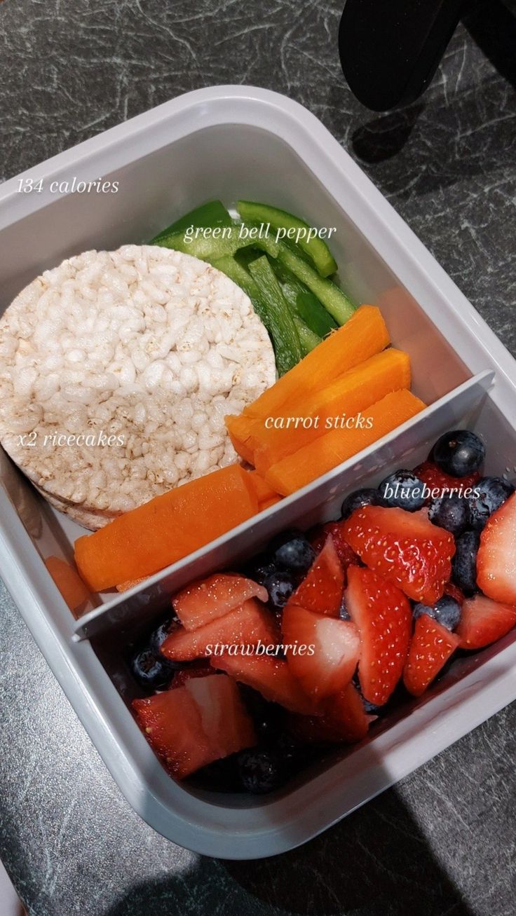 a plastic container filled with rice, fruit and veggies