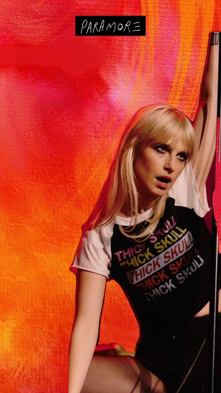 a woman with blonde hair is posing in front of a red and orange background holding a surfboard