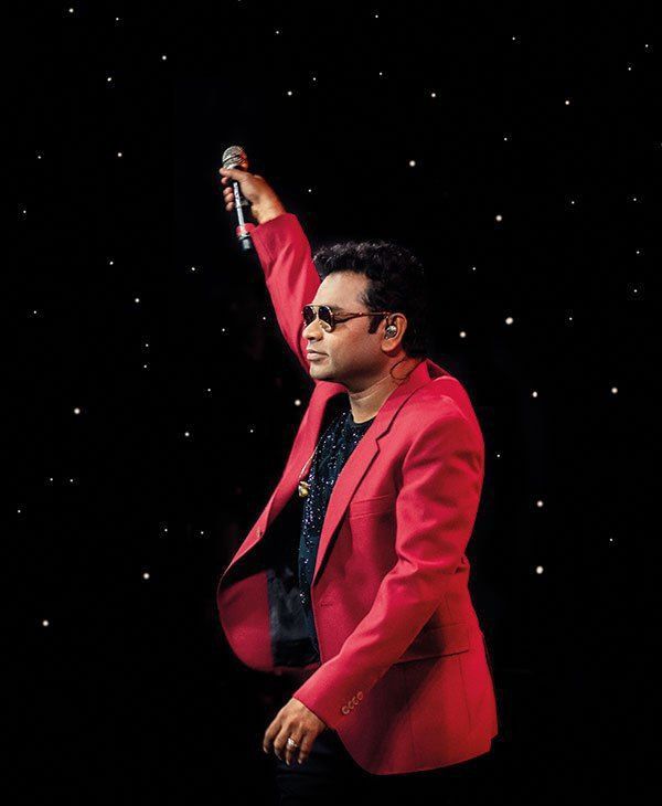 a man in a red suit and sunglasses holding a microphone