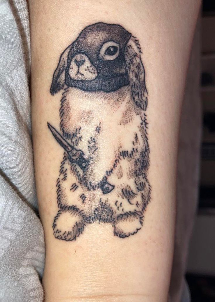 a tattoo on the arm of a person with a rabbit holding a knife in it's hand