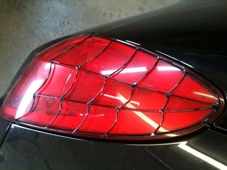 the tail light of a black car with a spider web design on it's side