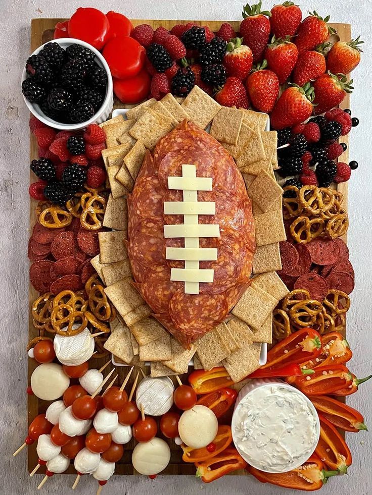 a football platter with crackers, fruit and dip