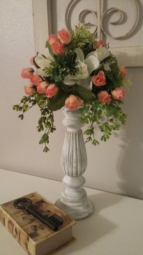 a white vase filled with flowers on top of a table next to an old book