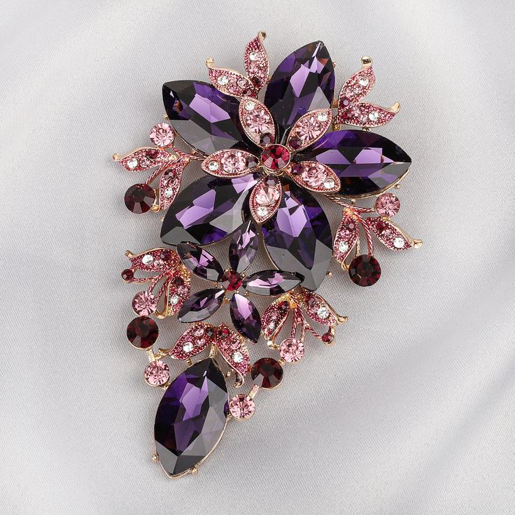 Description Turn simple into chic with a statement brooch like this Piper Floral brooch and make your own waves in fashion by bringing the brooches back. Nothing makes an outfit stand out more than an extravagant and shiny floral brooch. Large statement flower jewelry decorated with rhinestones and leaves with accenting colors with a pin backing for fabric wear. Size • Height: 5 in (12.7 cm)• Width: 3.25 in (8.26 cm) Quality Made from high-quality lightweight, solid gold coating metal alloy that Elegant Purple Flower Brooch, Flower-shaped Brooch For Party, Party Flower Shaped Brooch Jewelry, Flower Shaped Party Brooch, Broches Jewelry, Lady Suits, Statement Brooch, Brooch Dress, Lehenga Designs Simple