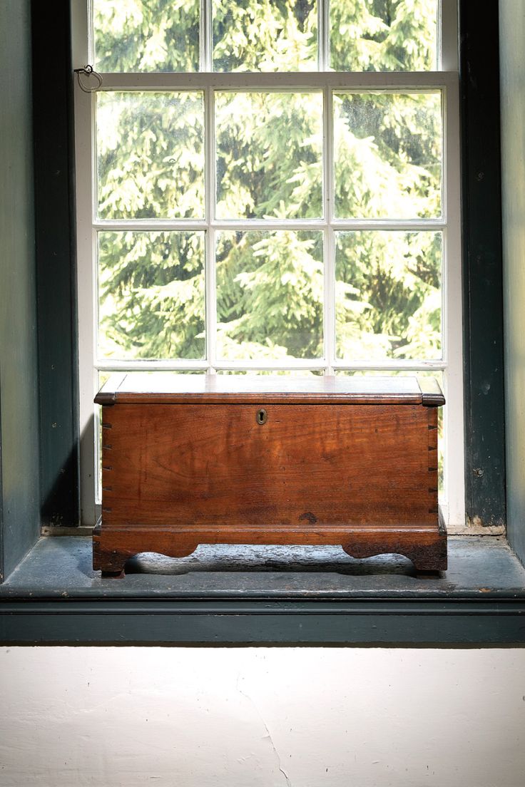 a wooden chest sitting in front of a window