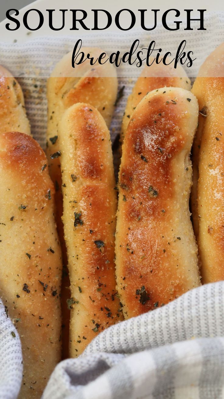 breadsticks with herbs and seasoning on them are in a basket, ready to be eaten