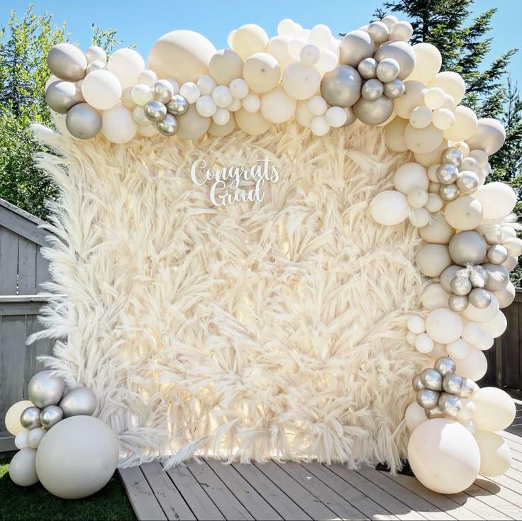 a white backdrop with balloons and balls on the ground in front of a wooden deck