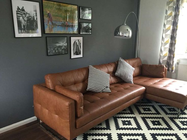 a brown leather couch sitting on top of a wooden floor next to a white and black rug