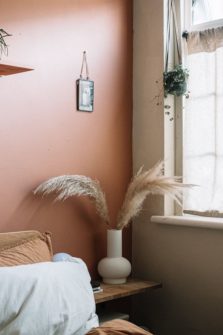 a room with a bed, window and plant on the table in front of it