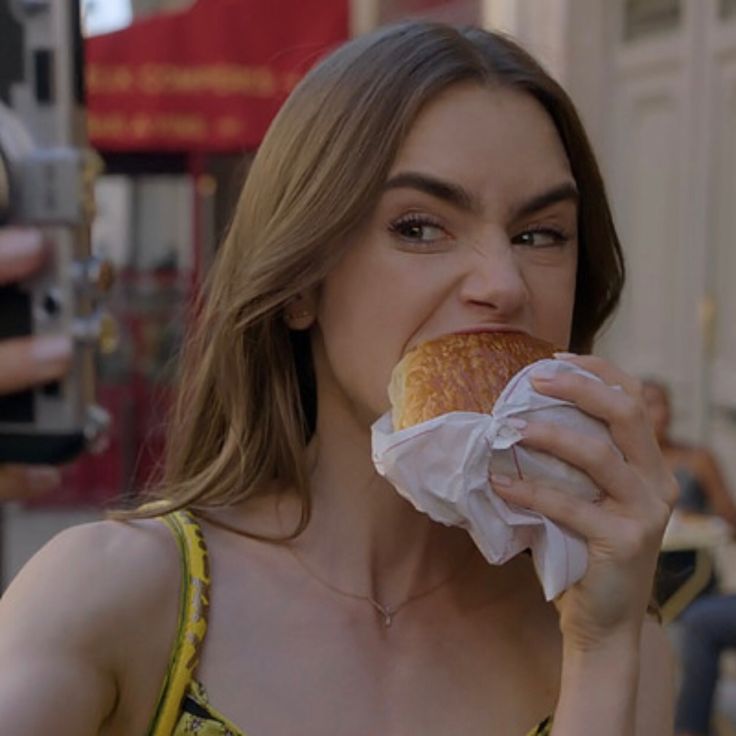 a woman eating a donut while holding a camera