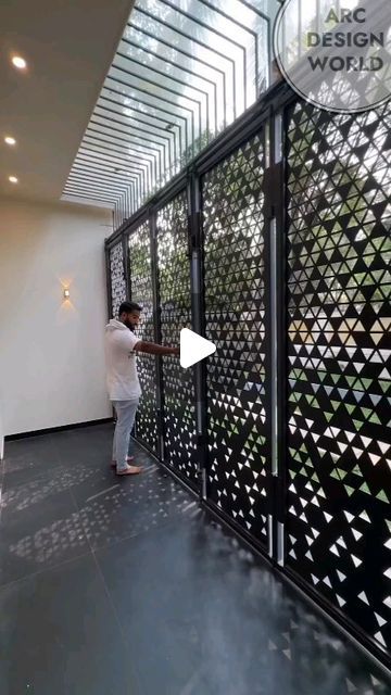 a man standing in front of a black and white wall with geometric designs on it