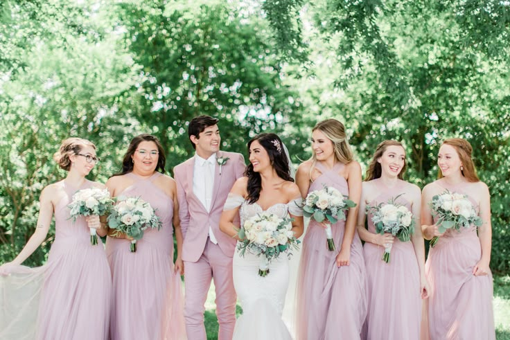 a group of people standing next to each other in front of trees and grass with flowers