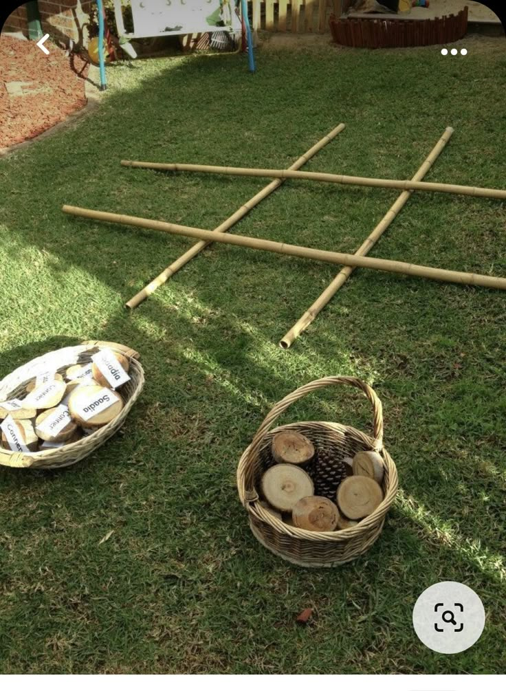 a basket full of logs sitting on top of a grass covered field next to a picnic table