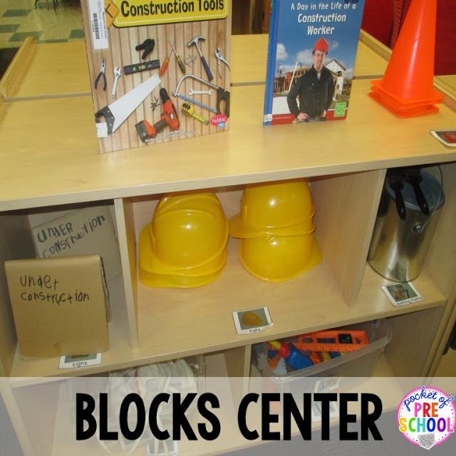 there is a shelf with books and construction hats on it that says blocks center in front of the bookcase