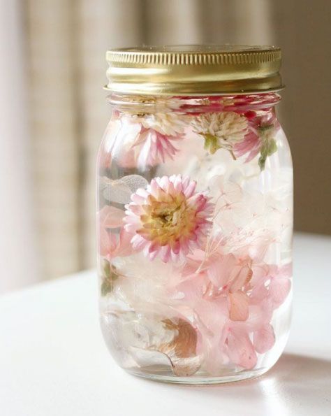 a jar filled with flowers sitting on top of a table