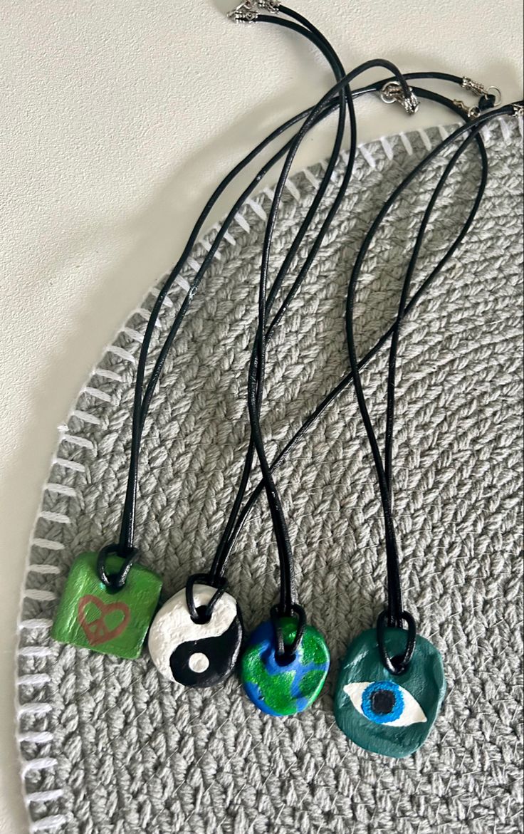 three necklaces are hanging on a circular plate with black cord and green beads, one has an eye