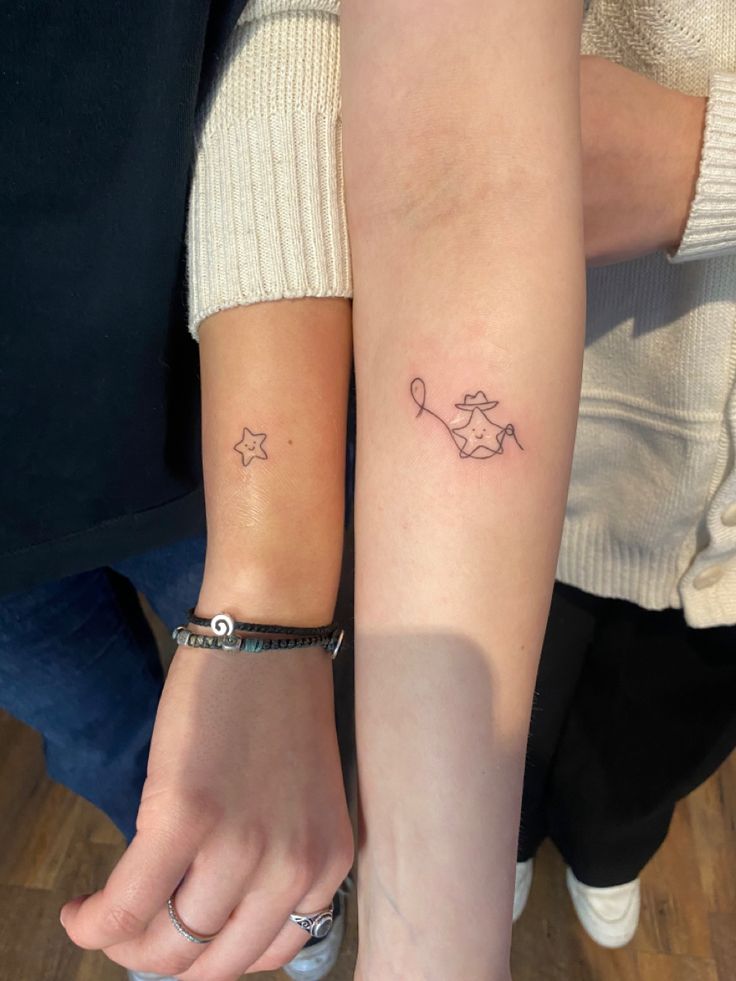 two people holding hands with tattoos on their arms, one has a star and the other has a fish