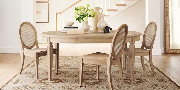 a table with chairs and a vase on top of it in a living room next to stairs