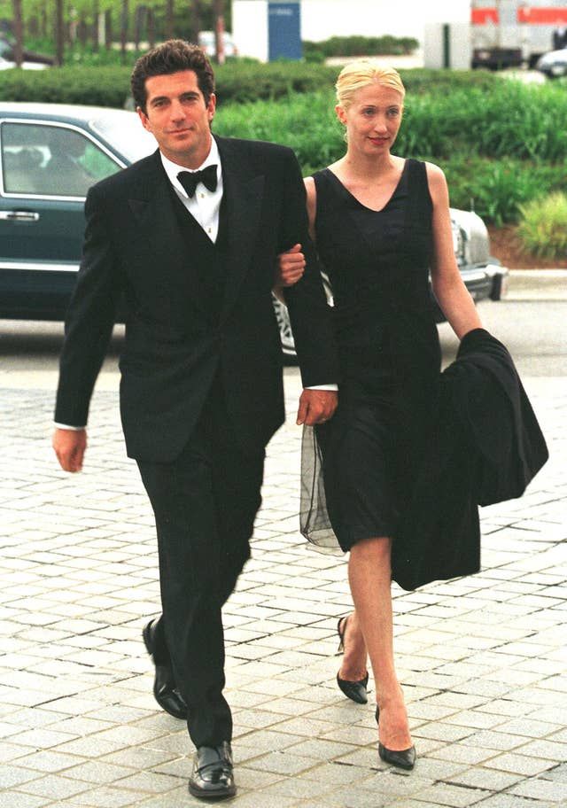 a man and woman dressed in black walking down the street with one holding an umbrella