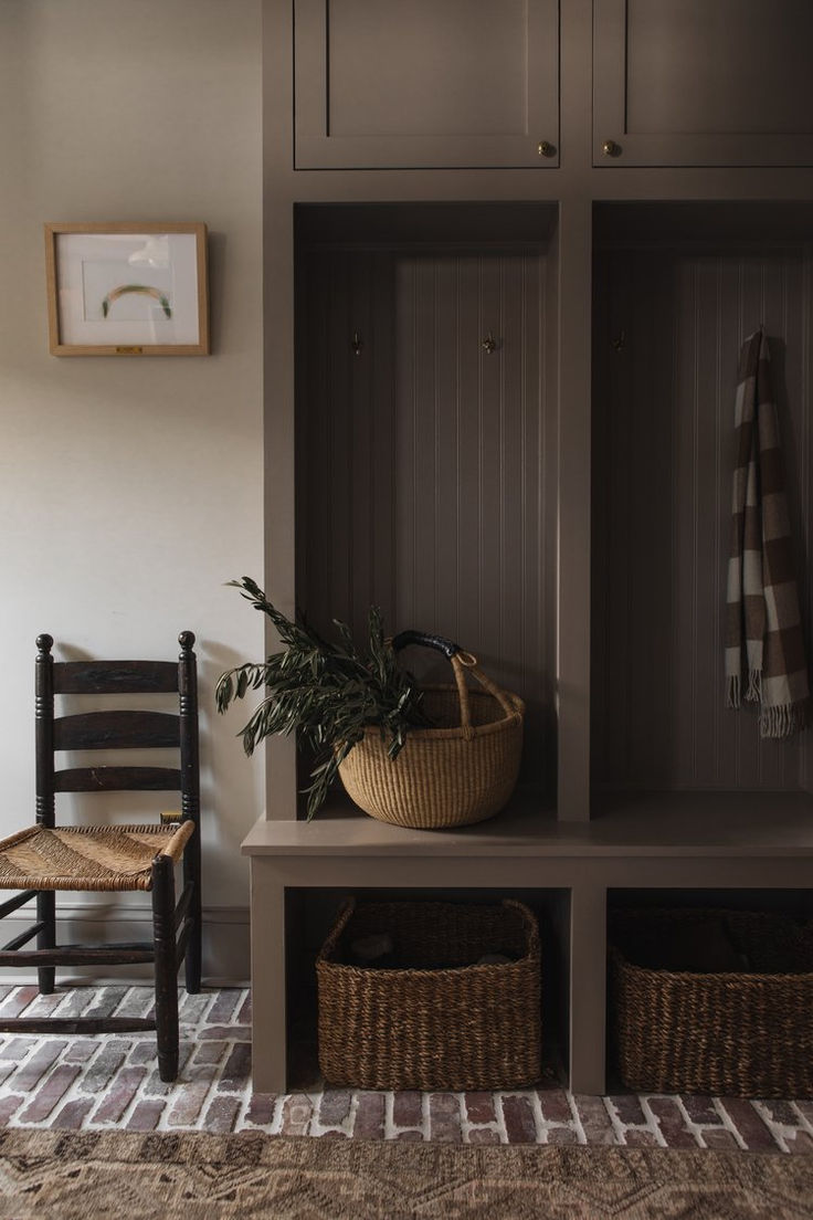 a wooden bench with two baskets on top of it next to a wall mounted coat rack