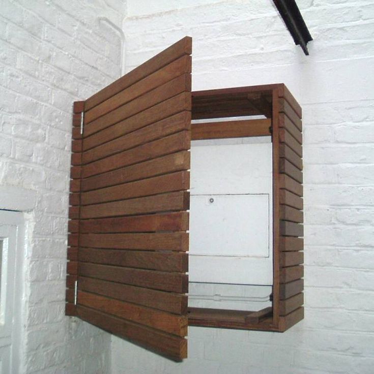 an open wooden door on the side of a white brick wall with wood slats