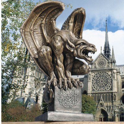 a statue of a gargoyle in front of a cathedral