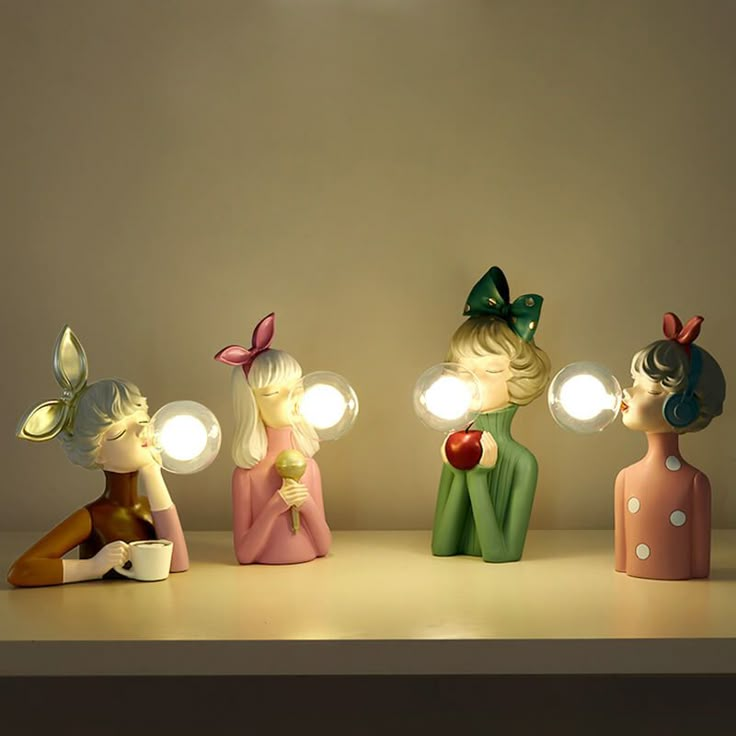 three little figurines are sitting on a shelf with lights in their hands and one is holding an apple