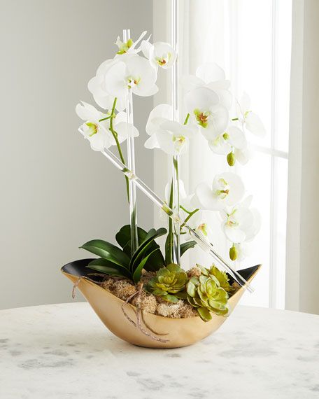 white orchids and succulents in a gold bowl on a table