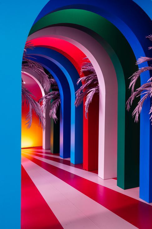 an archway with palm trees in it and multicolored walls on the other side